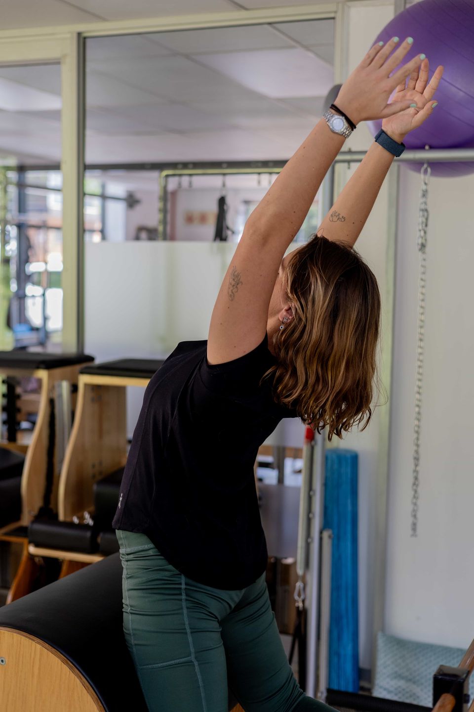 An overhead side stretch over the ladder barrel in a Pilates stretch class in Randburg