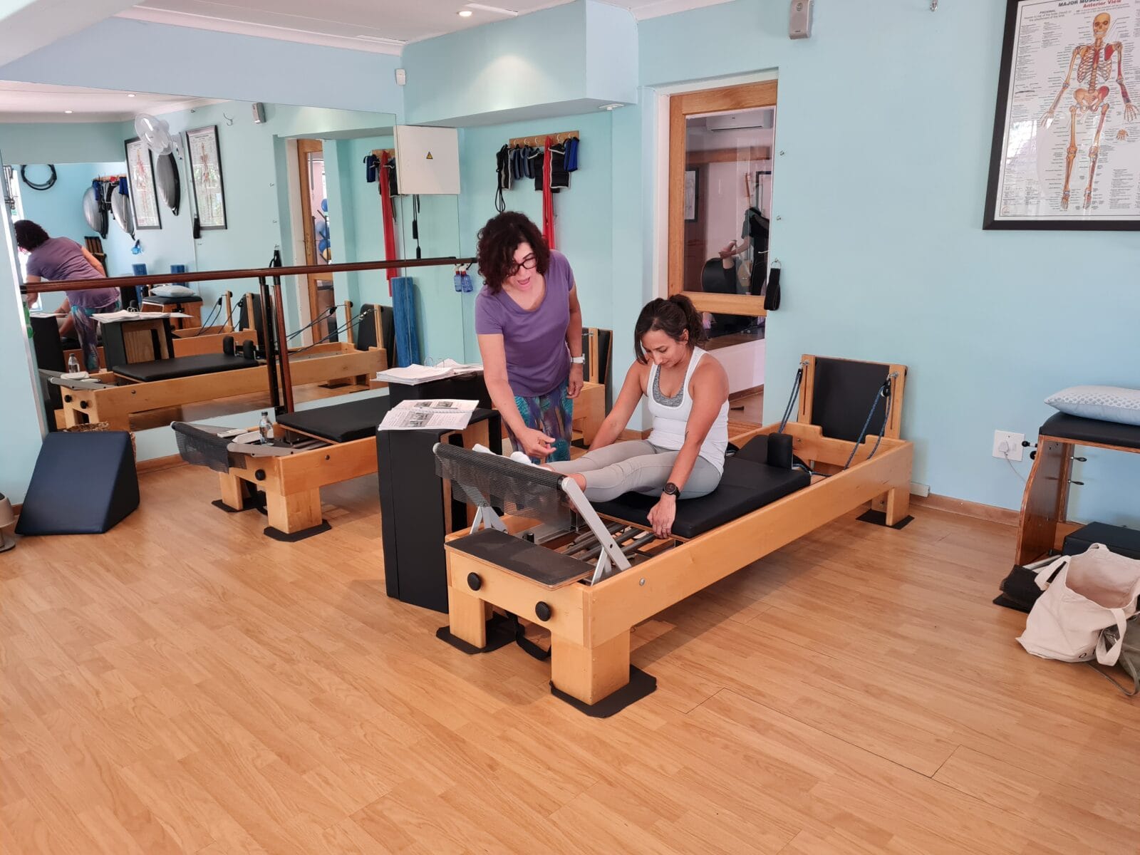 Pilates Instructor guiding student using pilates bench